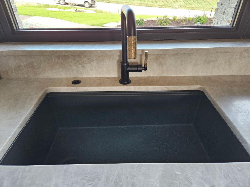 Black composite undermount kitchen sink with matte black and brass faucet
