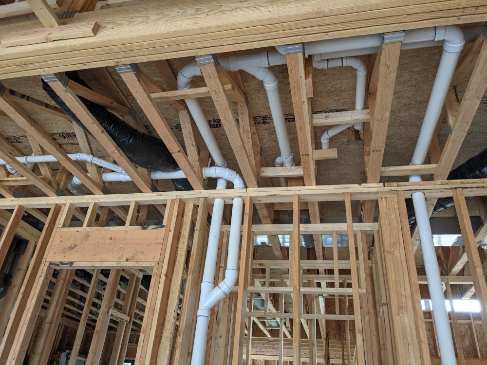 PVC drain-waste-vent rough-in through floor framing in a new build