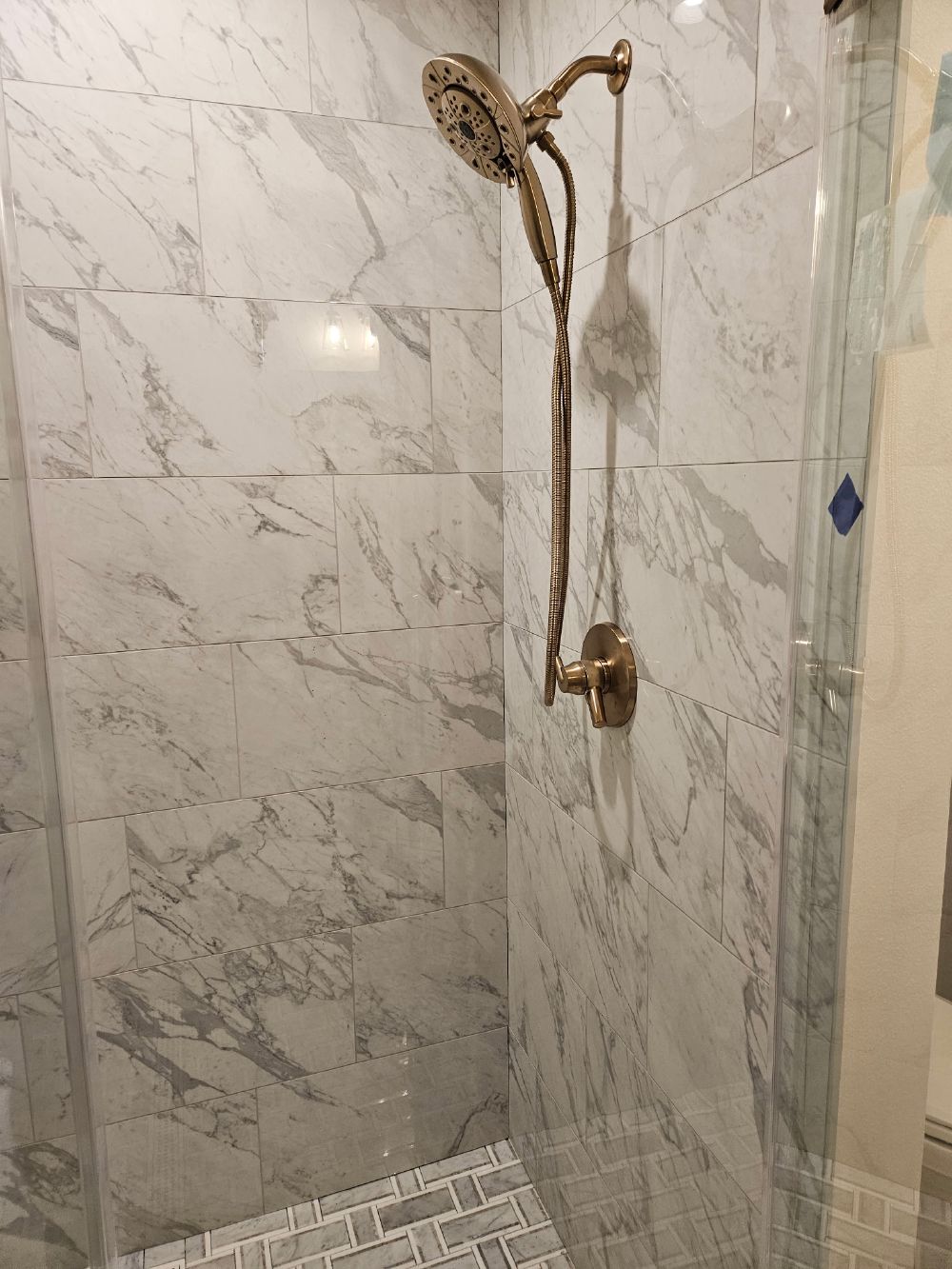 Marble-look tiled shower with brushed gold multi-function shower head